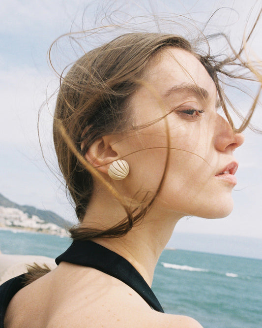 girl wearing shell earrings on the beach