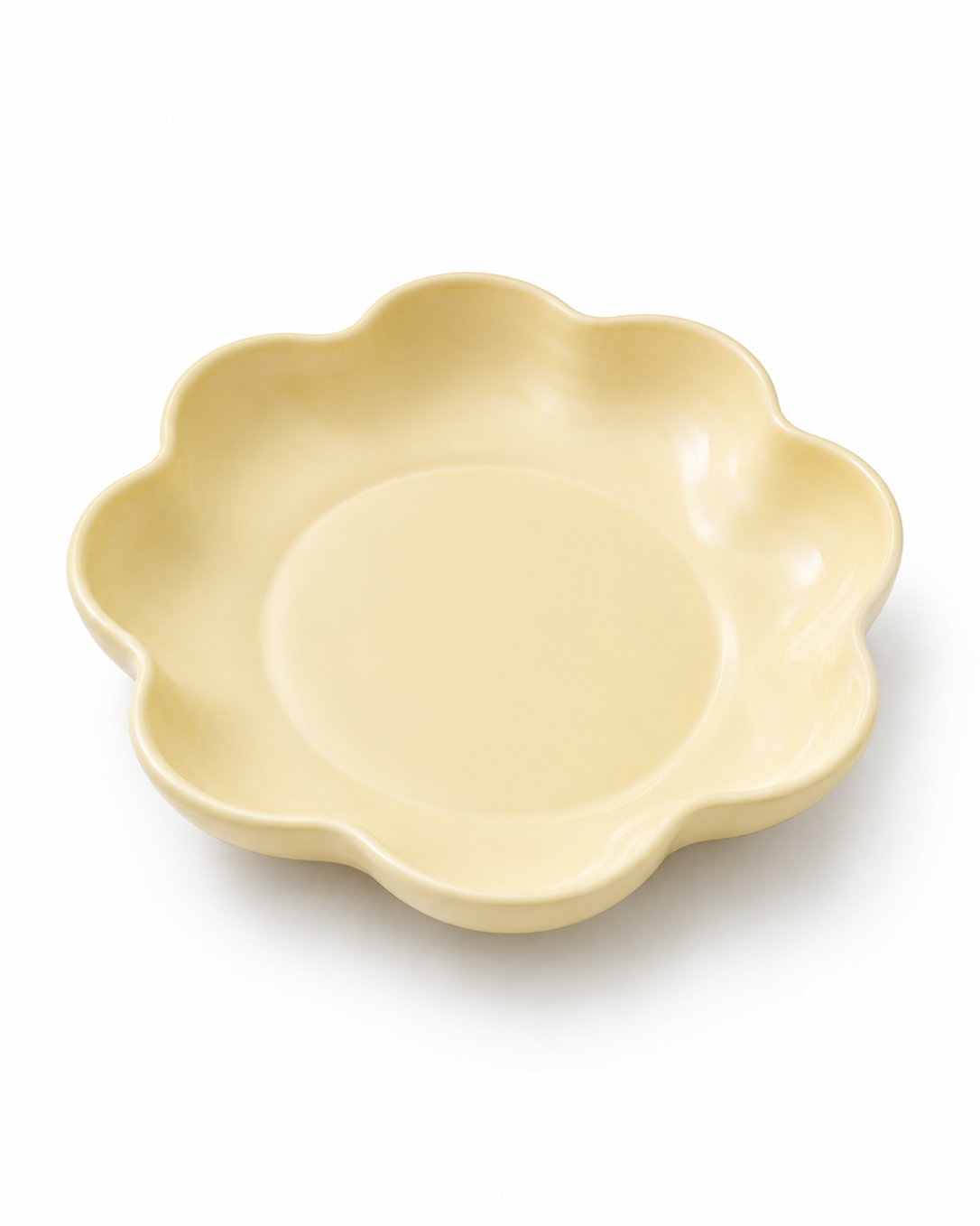 A pale yellow ceramic plate with a scalloped, flower-like rim, shown from a top-down angle on a white background.